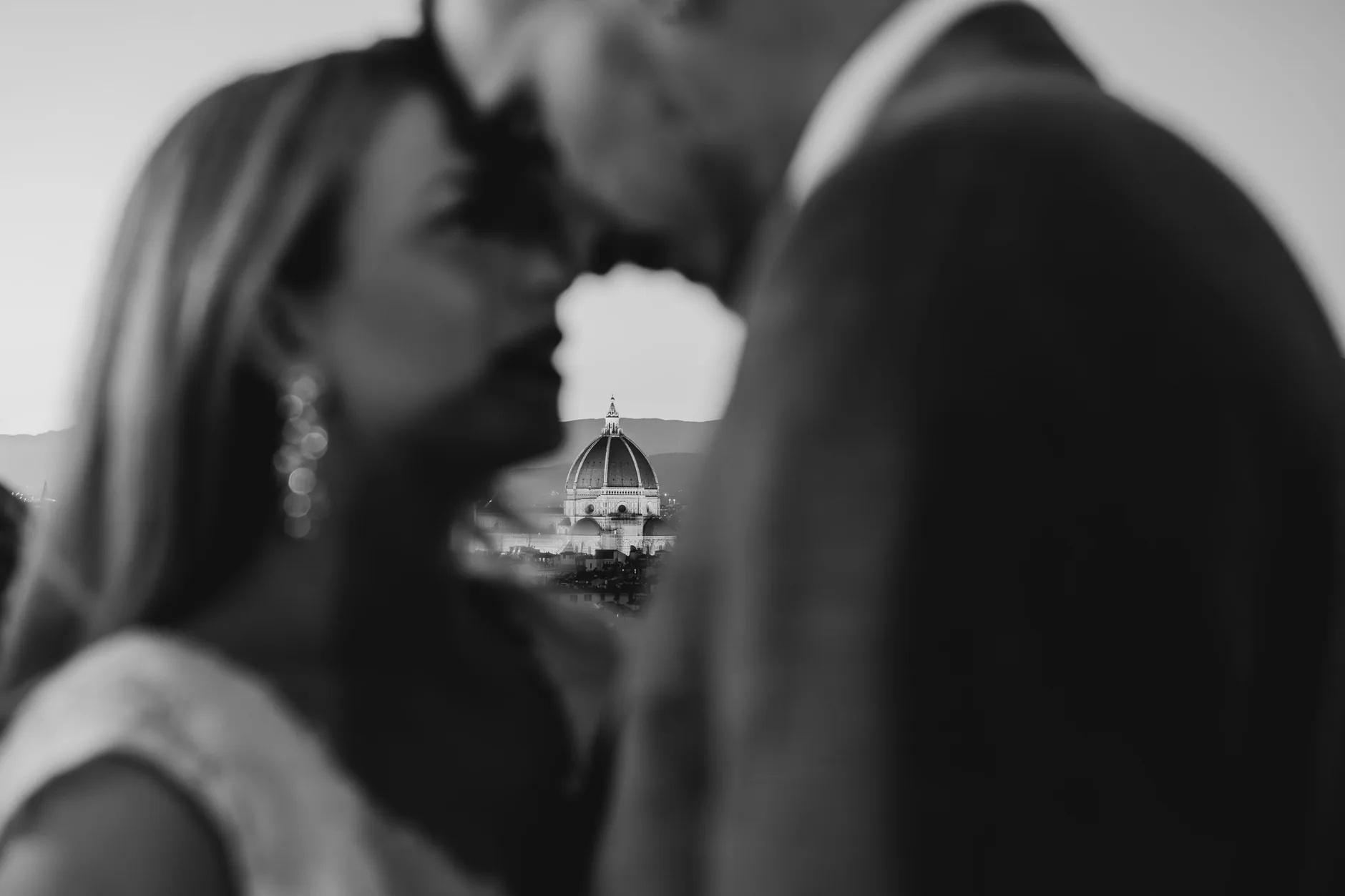 La cupola di Firenze incorniciata tra gli sposi durante un bacio, in bianco e nero