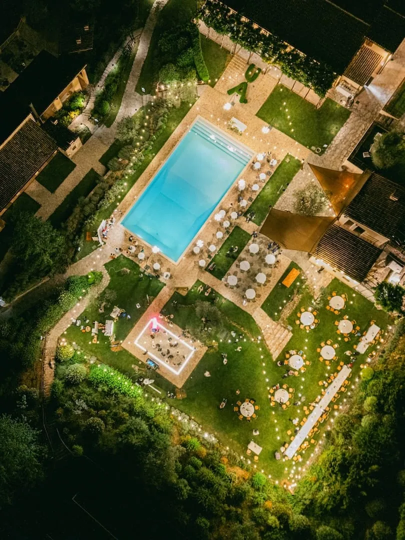 Aerial view of an evening wedding reception with pool and string lights at an Italian estate