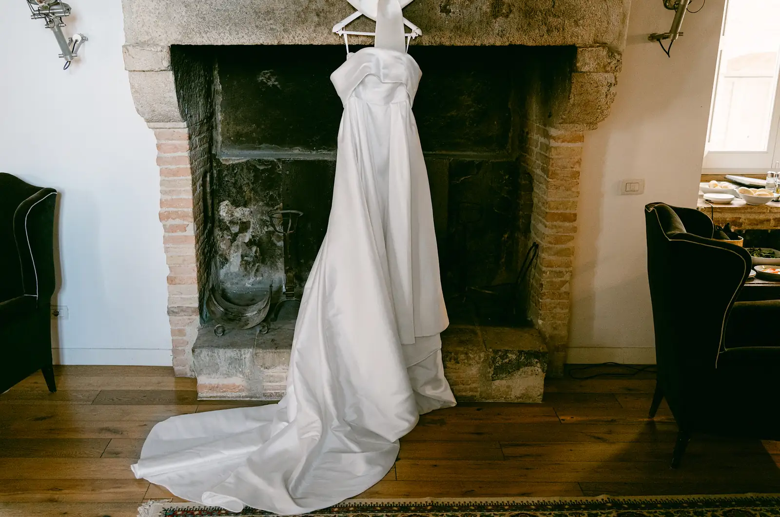 L'abito da sposa appeso davanti a un camino in pietra