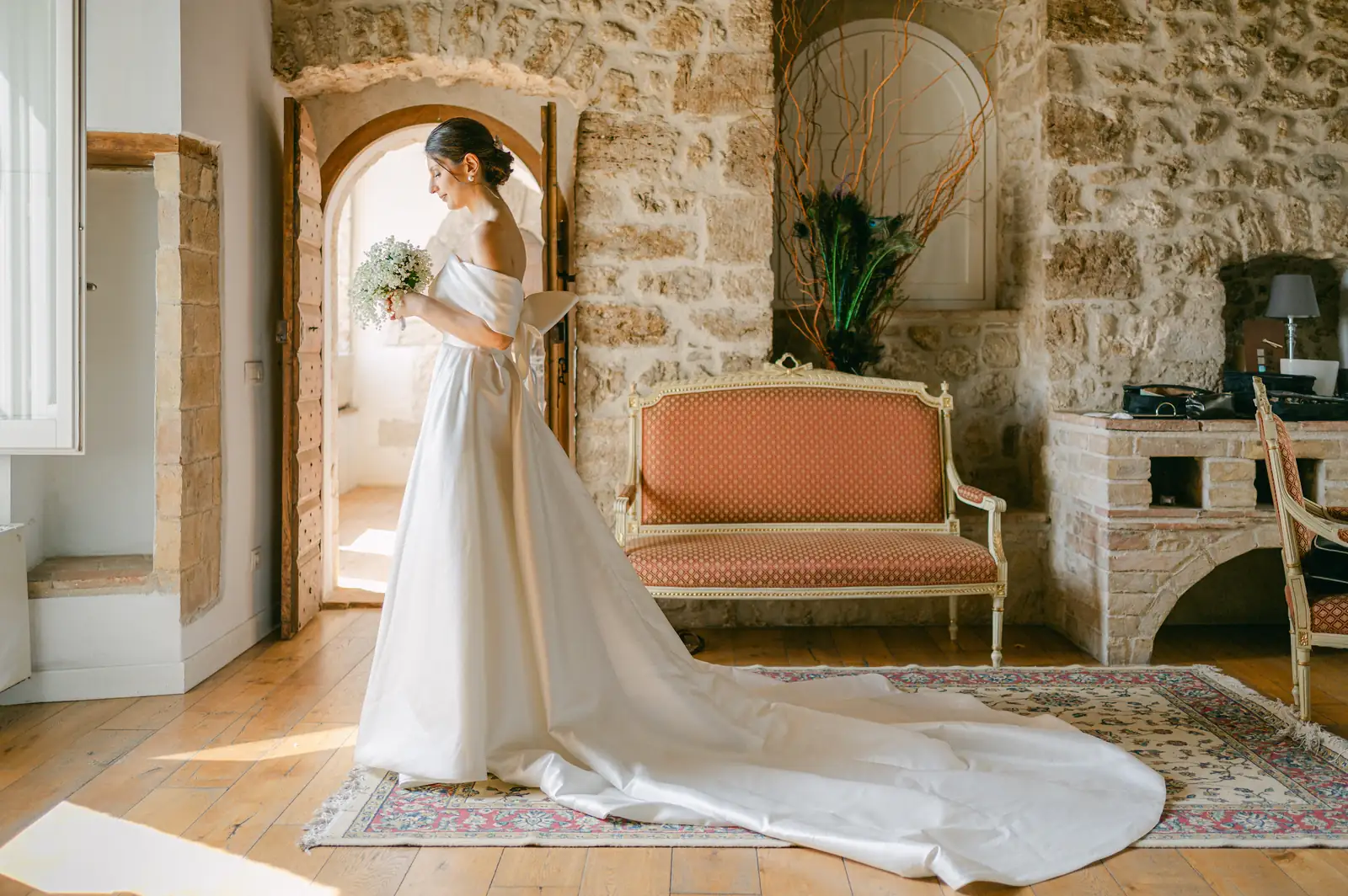 La sposa con il lungo strascico dell'abito in una sala del borgo