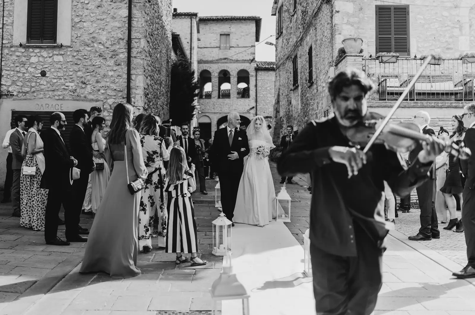 Un violinista accompagna l'arrivo della sposa tra le case in pietra