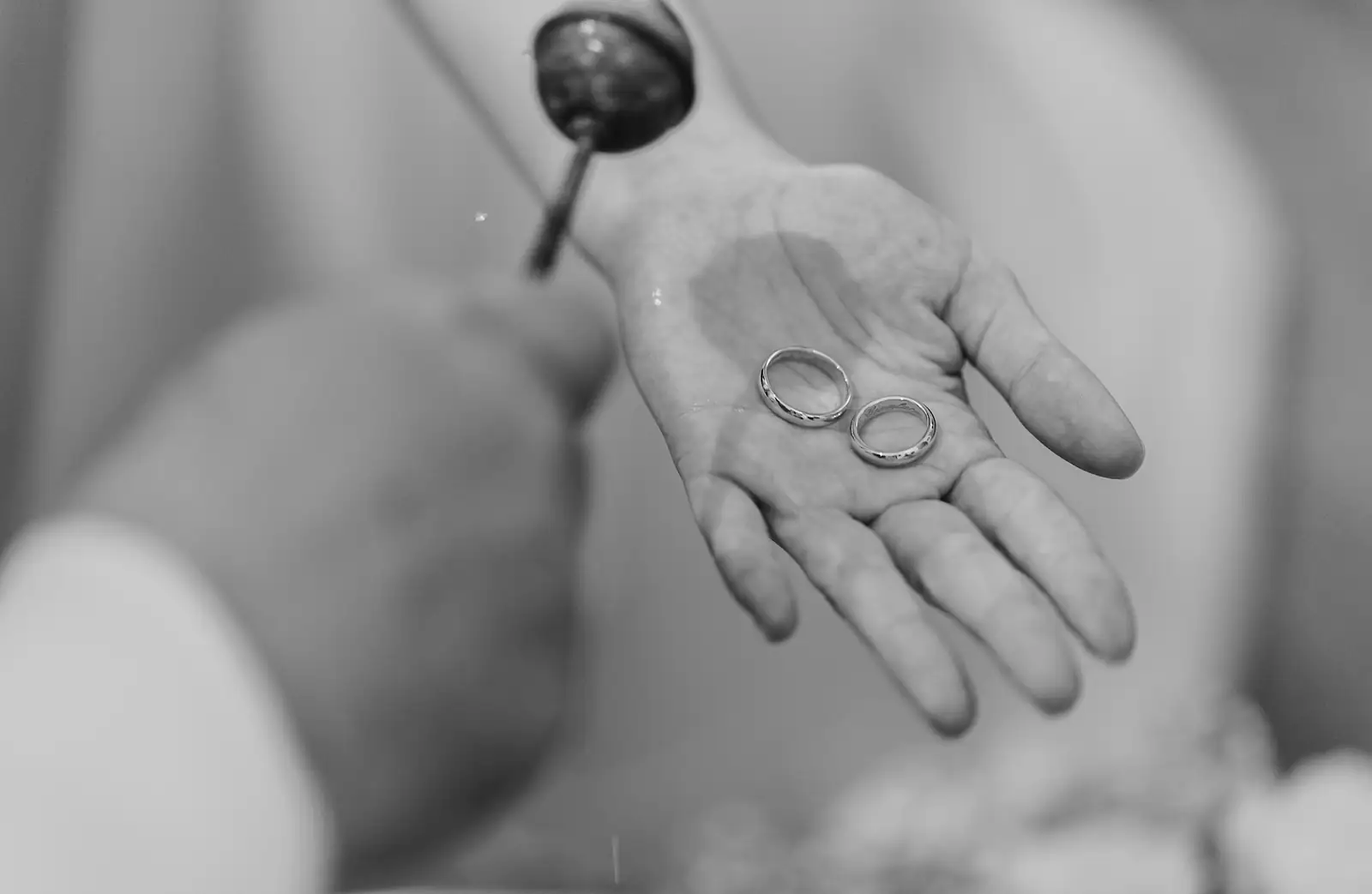 Le fedi nuziali sul palmo di una mano, in bianco e nero