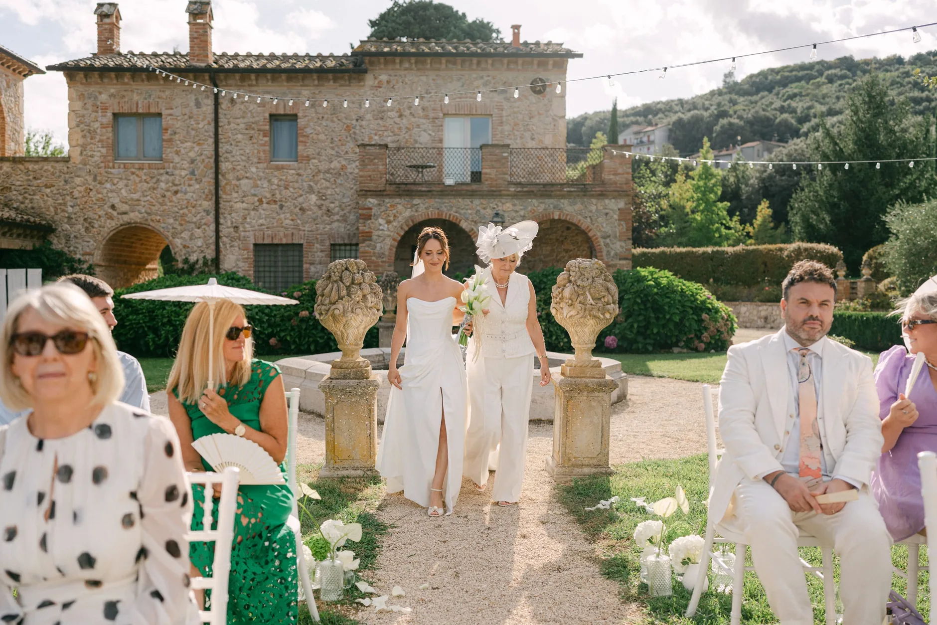 Christina percorre la navata in giardino, con la villa in pietra alle spalle