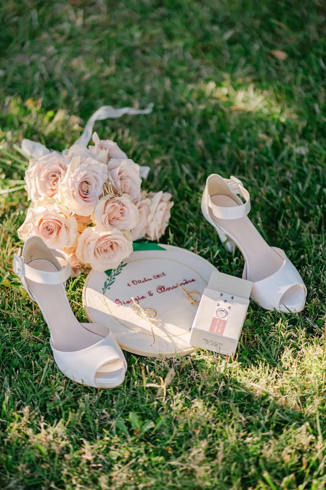 Le scarpe da sposa e il bouquet di rose appoggiati sul prato