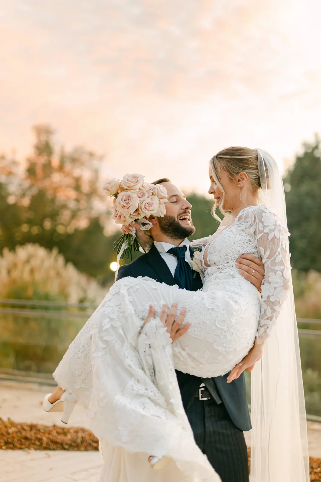 Lo sposo solleva la sposa con il cielo del tramonto sullo sfondo