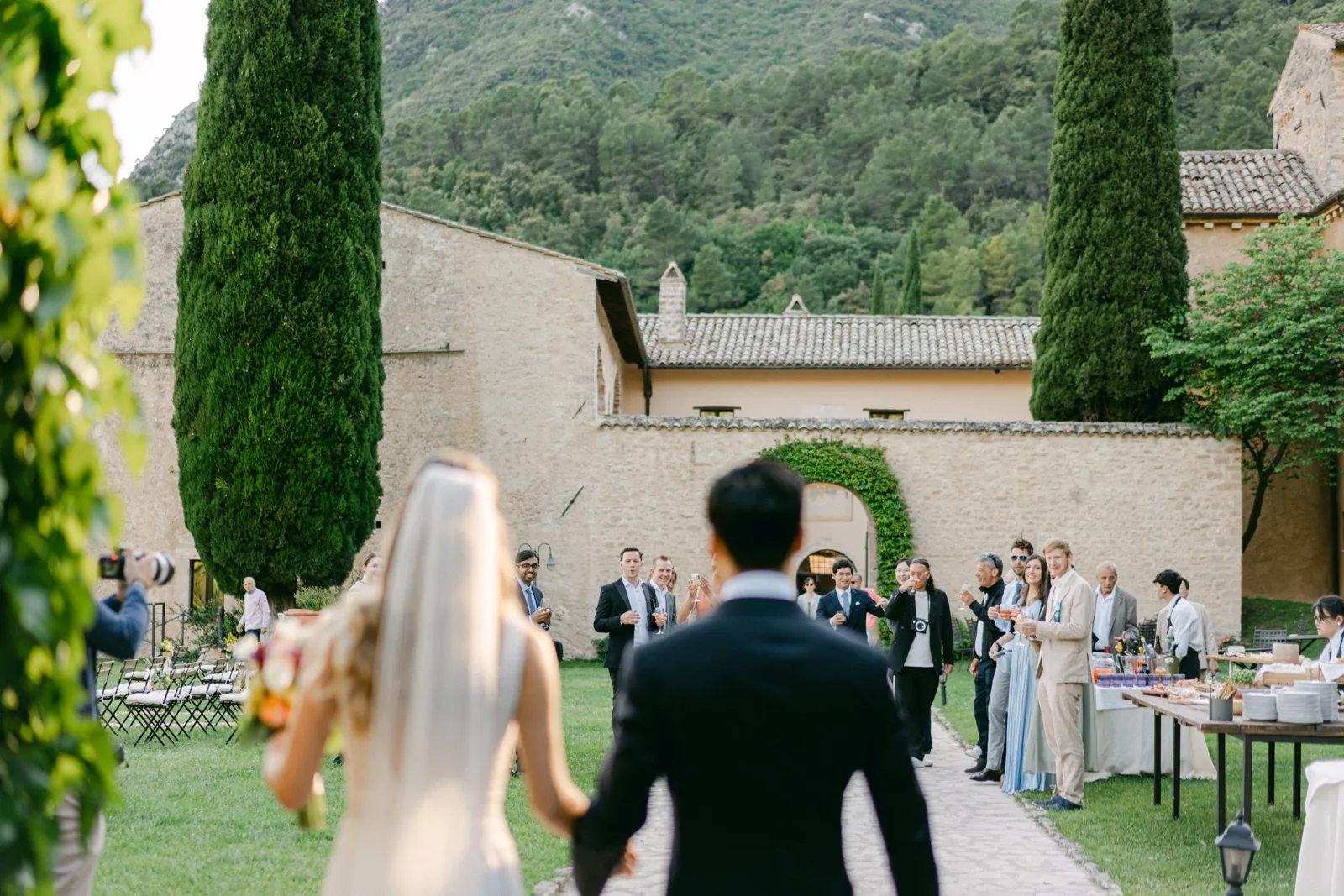 Gli sposi raggiungono gli invitati per l’aperitivo nel giardino dell’abbazia