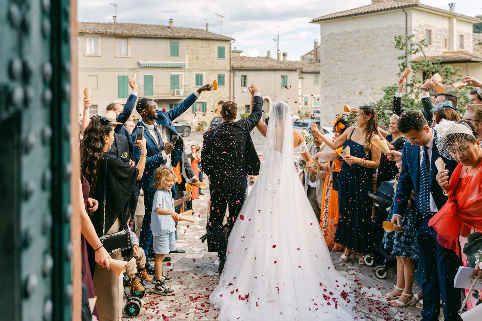 La sposa di spalle con il lungo velo tra i coriandoli