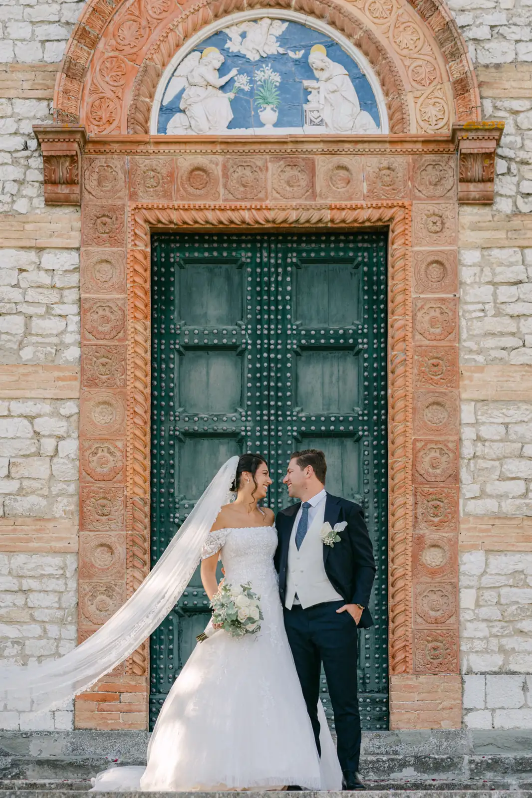 La sposa con il velo davanti al portale della chiesa