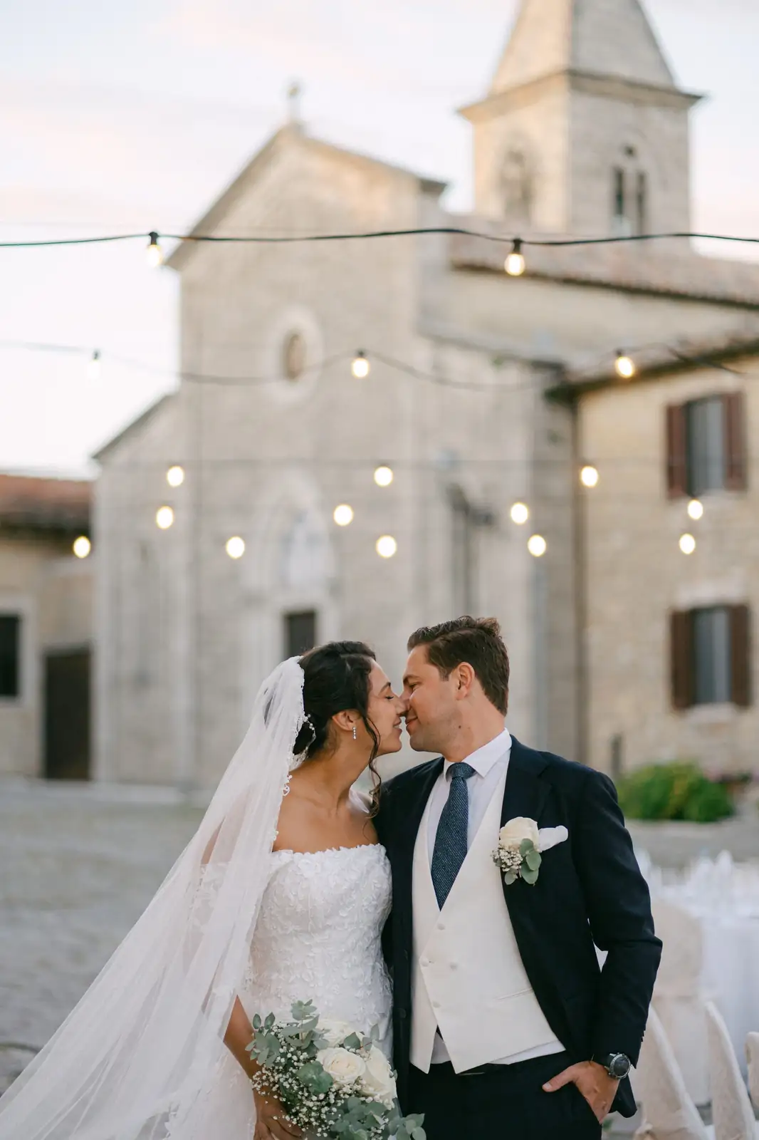 Gli sposi nella piazza del Castello di Titignano con il campanile al tramonto
